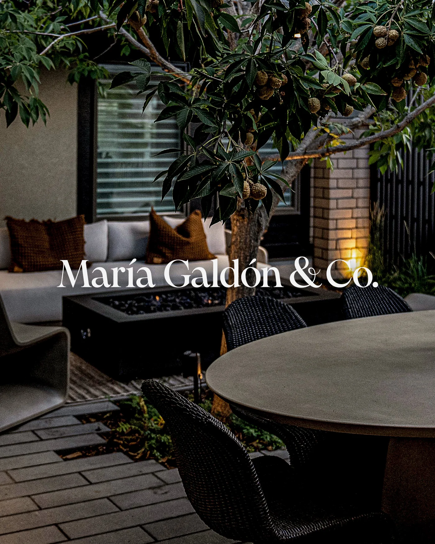 The Mar&iacute;a Gald&oacute;n & Co. wordmark over a lit courtyard at dusk.