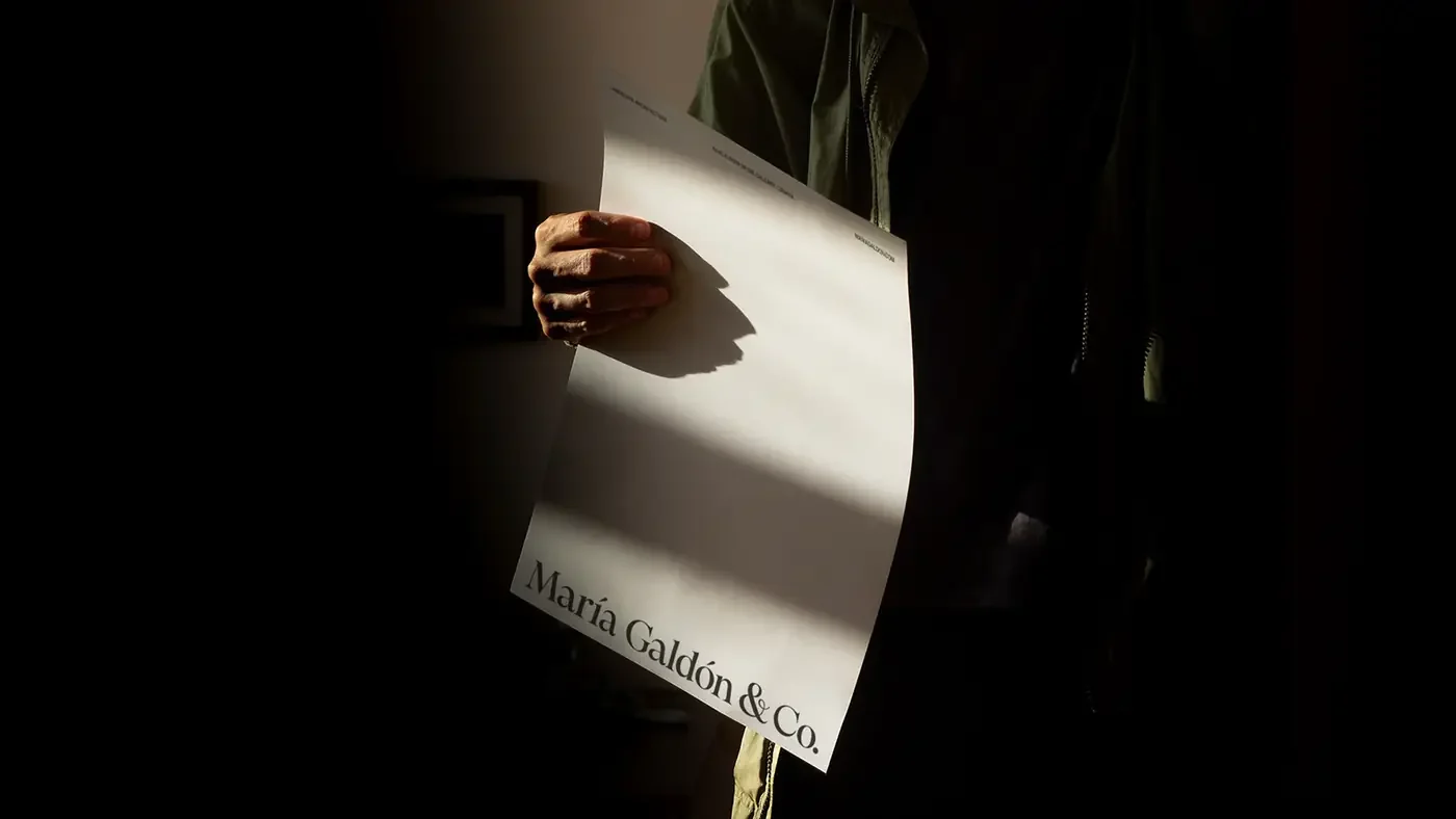 A hand holding the letterhead in raking light.