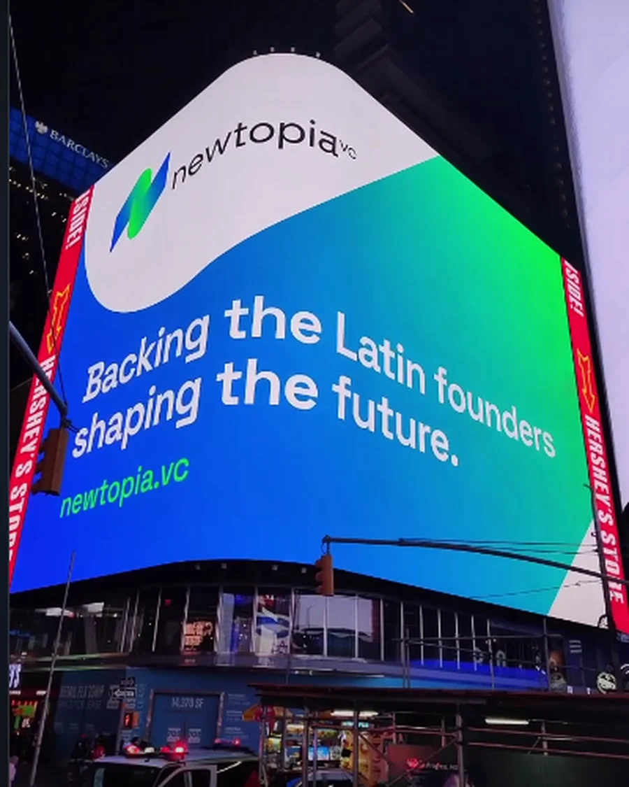 The Newtopia VC brand lit up on a billboard in Times Square at night
